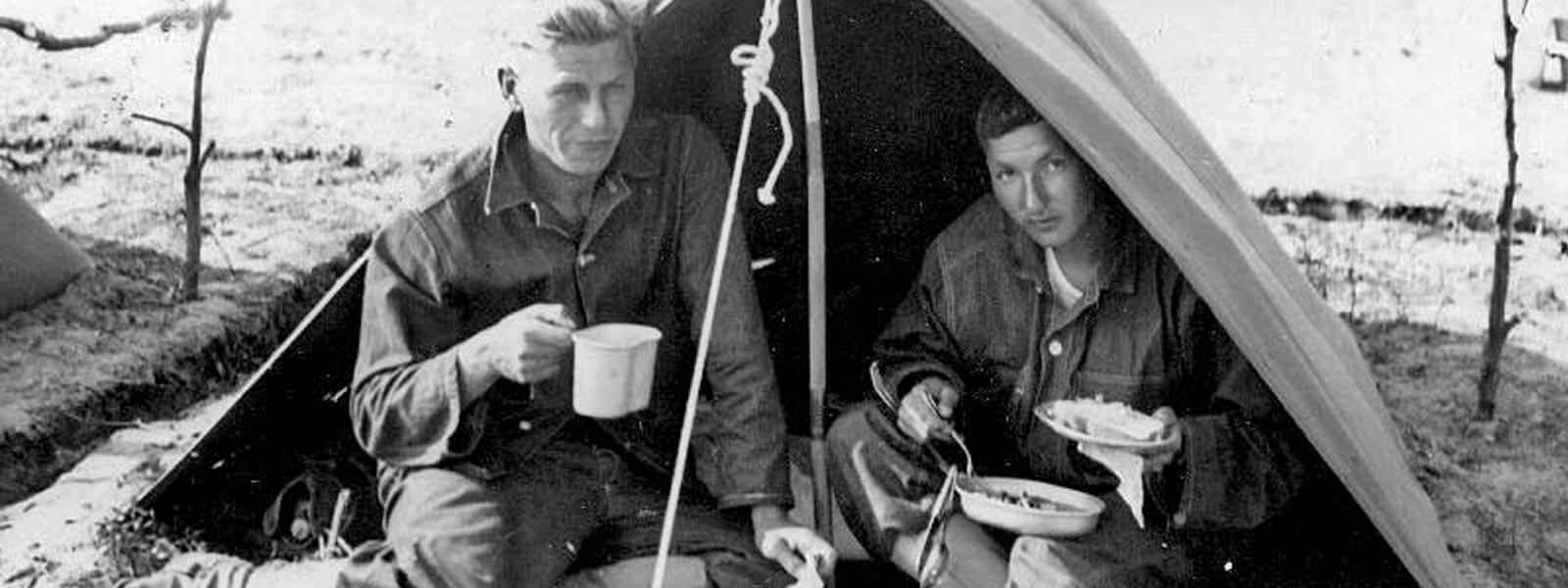 photo of two soldeiers eating in a pup tent