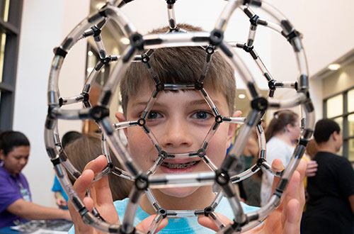 photo of a boy holding a toy molecule