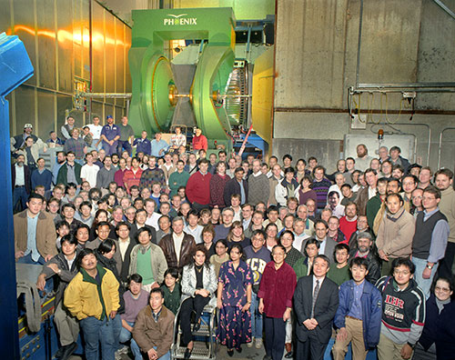 A group of researchers standing in front of the PHENIX detector at RHIC