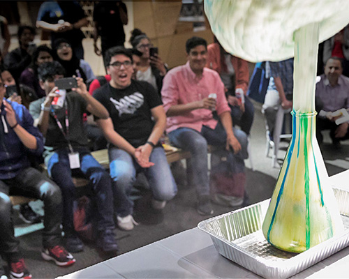 photo of audience watching foam erupt from a beaker