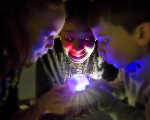 photo of children lookng at glowing ball