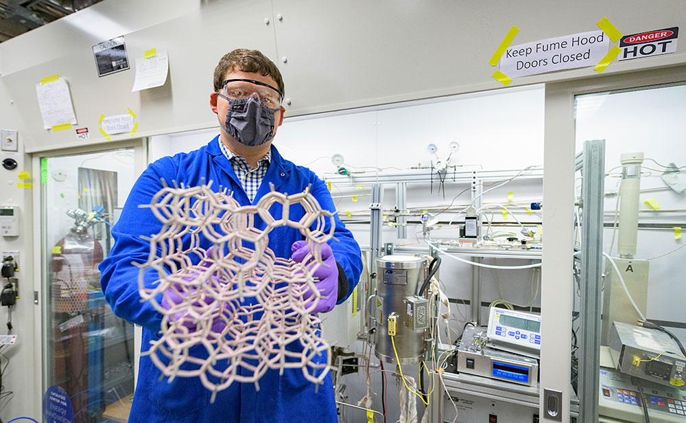 Photo of Mark LaFollette displaying a large structural model of a zeolite