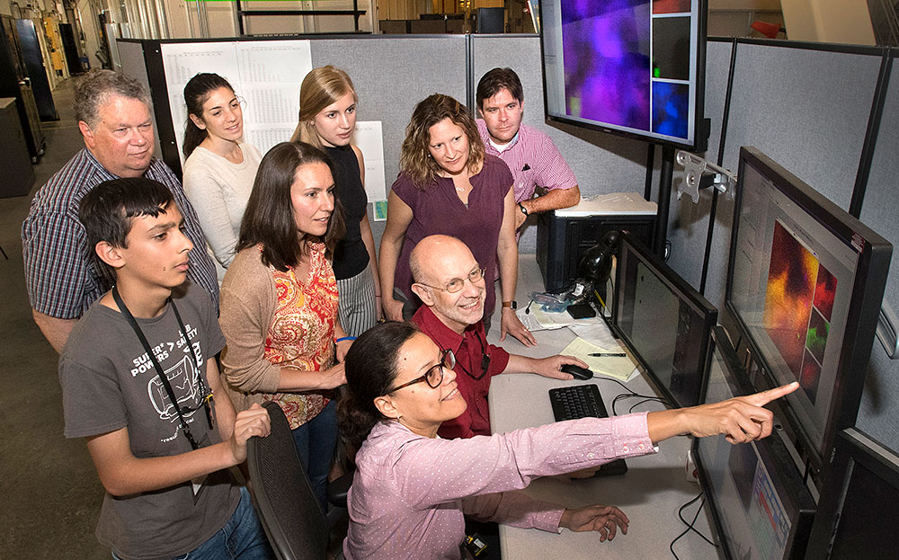 Photo of Aleida Perez and Juergen Thieme looking at data with students and teachers