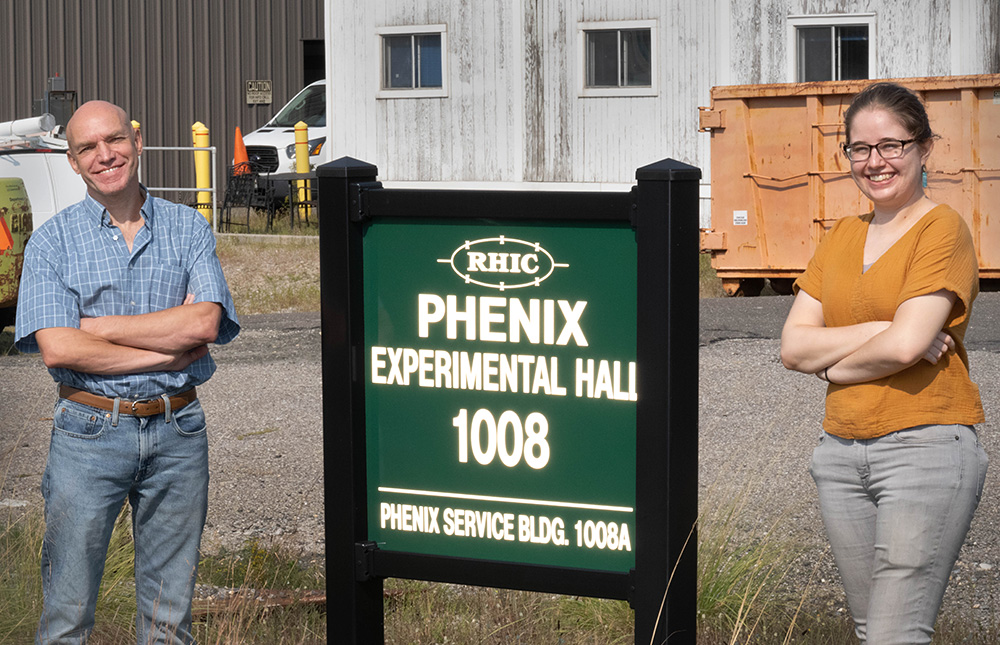 Photo of Alexander Bazilevsky and Nicole Lewis outside the experimental hall that housed the PHENIX