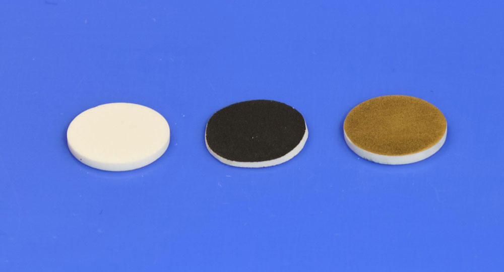 Photo of a white disk, black disk, brown disc placed in a row on a bright blue background