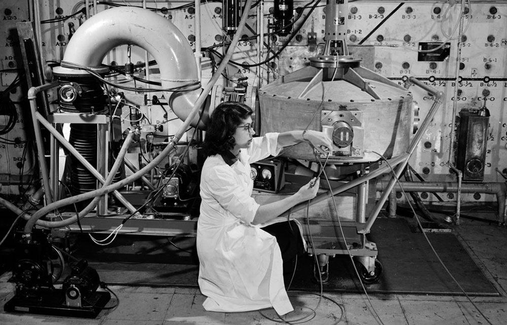 Black-and-white photo of researcher works with a piece of equipment known as the "fast neutron