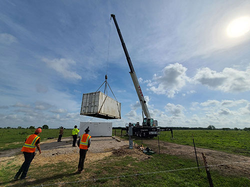 Photo of technicians lowering a container using a crane