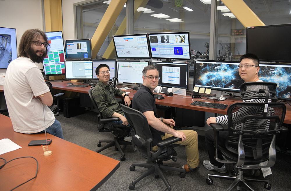 Johnny Pelliciari, Yao Shen, Mark Dean, and Wei He pose in a row in front of computer screens