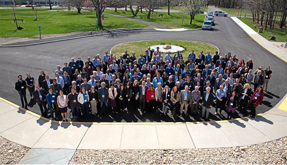 A large group of people smile up at a camera