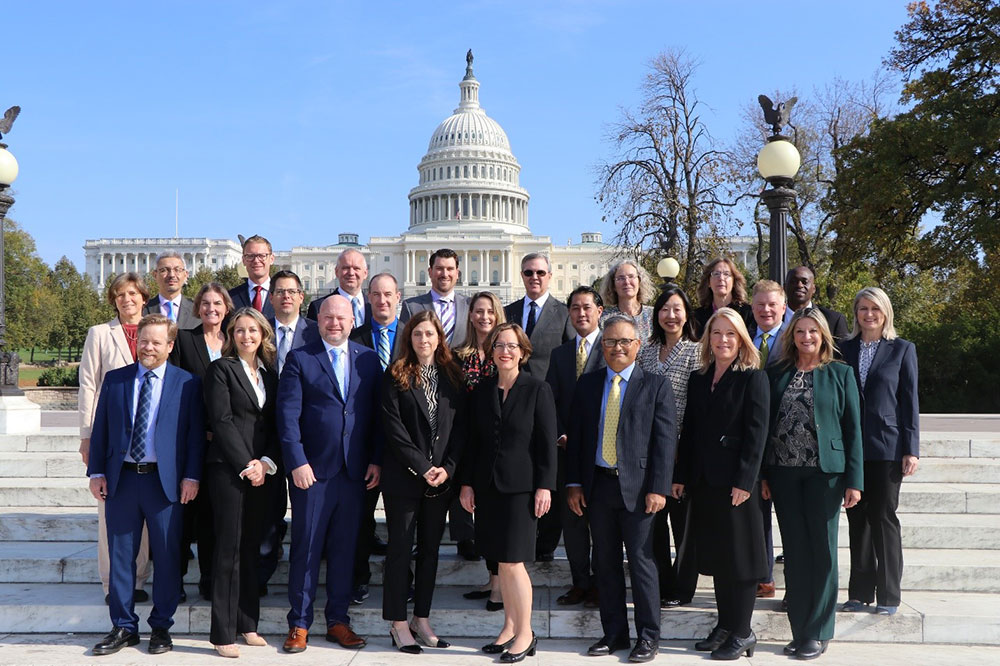 Group of adults pose with Capitol building in the backgroun