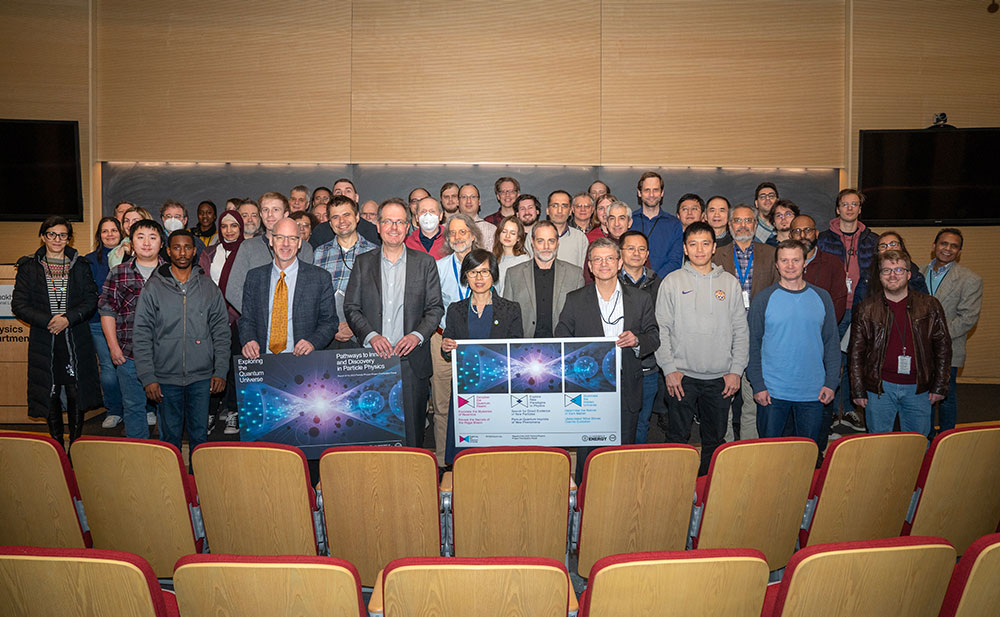 Group poses on stage with P5 presentation posters