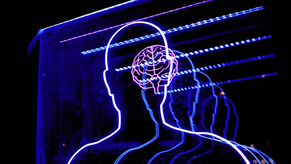 neon lights show the outline of the human body overlayed with an outline of the brain