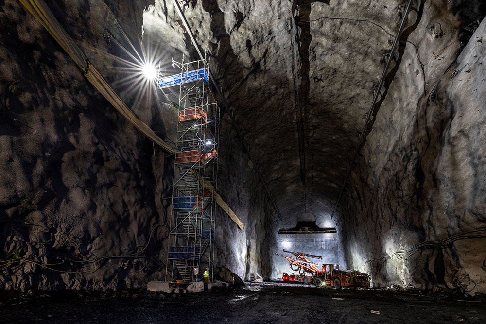 Spotlights illuminate a cavern, scaffolding, construction equipment and workers
