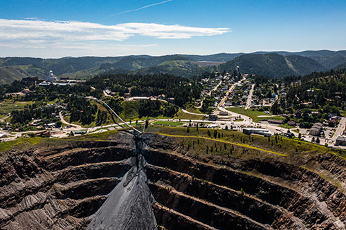 A large excavation site with green hills in the background