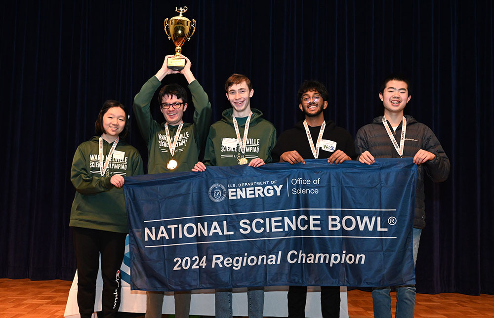Five students hold a banner that reads National Science Bowl 2024 Regional Champion. One student hol