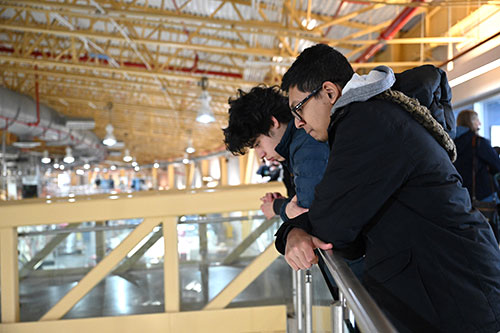 Two students lean on a railing to view an experimental floor