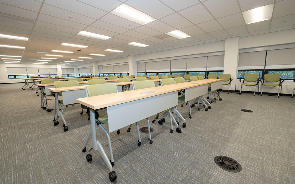 Conference room filled rows of long desks with green chairs