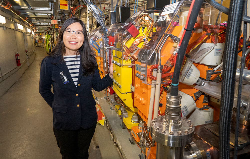 A woman stands next to large magnets in a long hallway