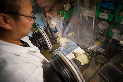 Scientist in a white lab coat working in a glove box.