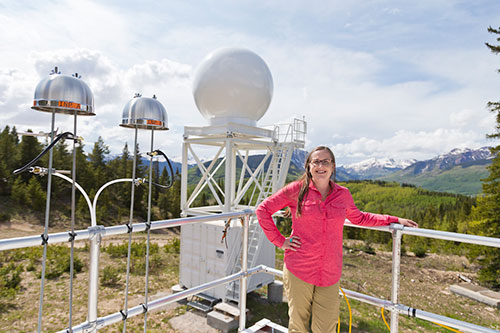 Allison Aiken stands on an instrument platform and rests her left arm on its railing. Two ice-nuclea