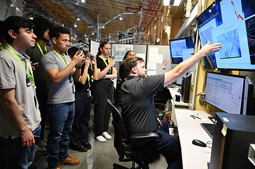 Students gathered around monitors showing data