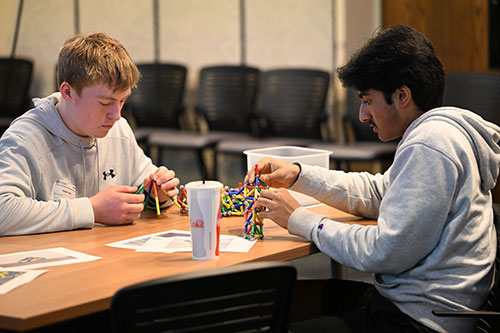 Two students building small structures with colorful magnetic toys