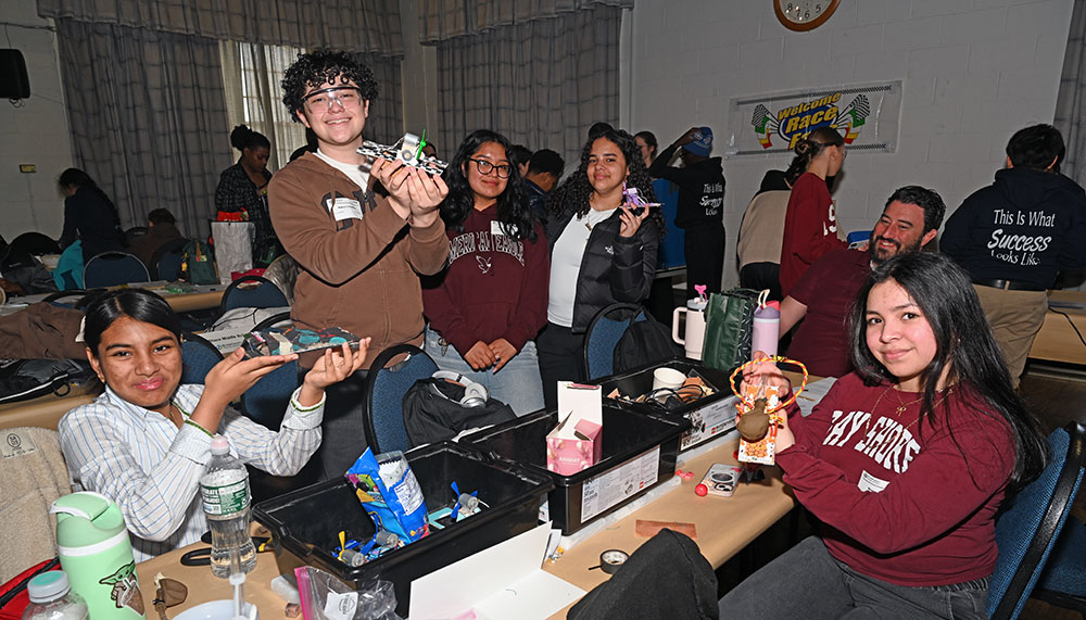 A group of students hold up small maglev vehicles
