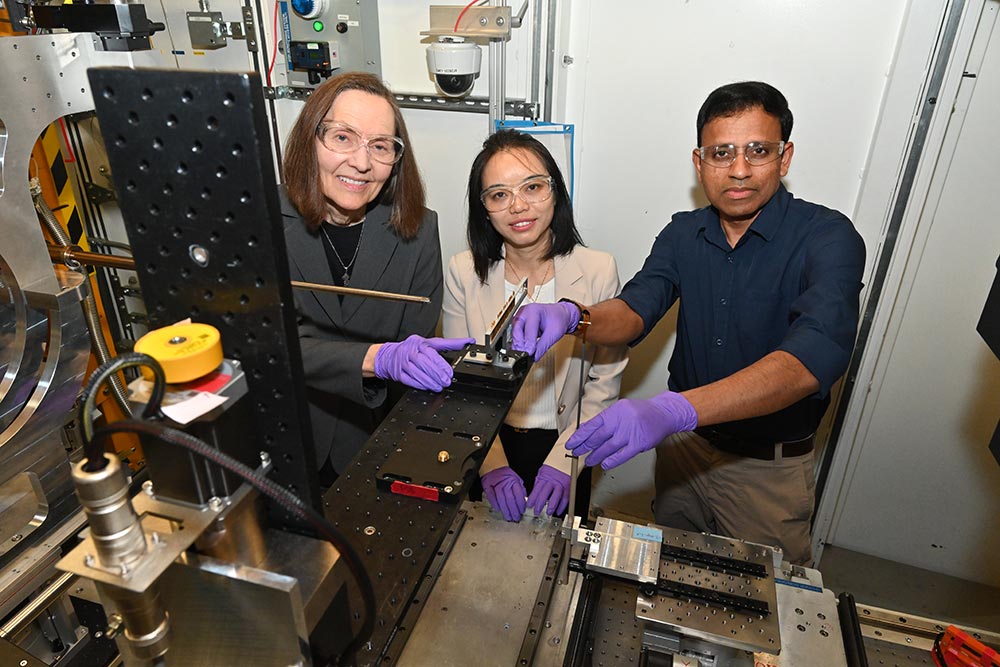 Study co-authors in a lab setting working with scientific equipment, wearing safety glasses and purp