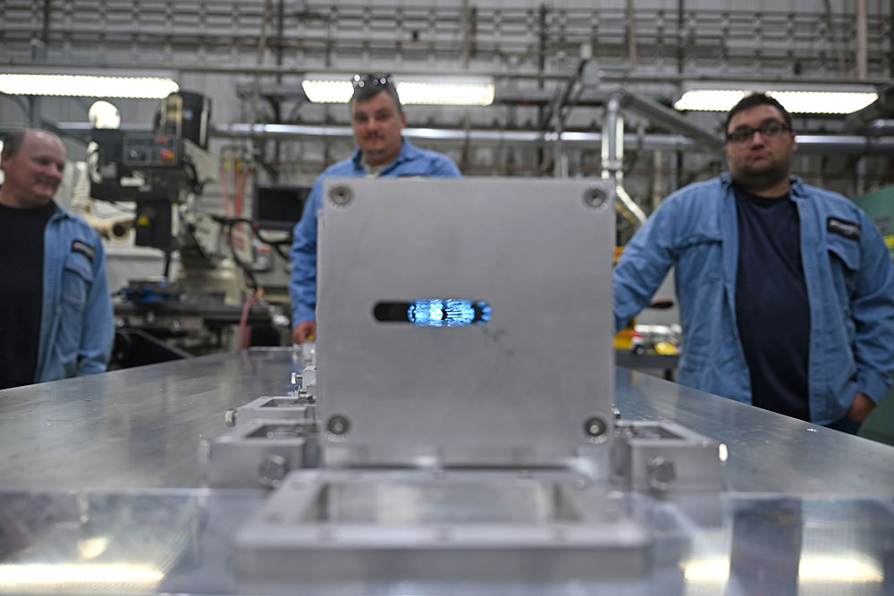 beam of light shining through the array with Mechanical Support Group staff in the background.