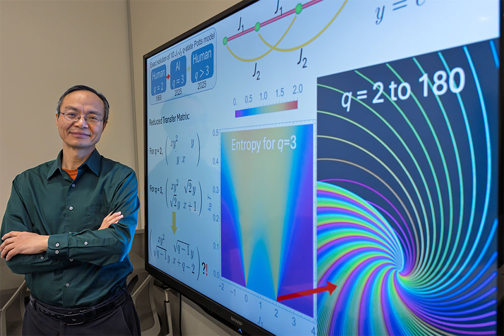 Weiguo Yin stands by a screen displaying equations used in his work