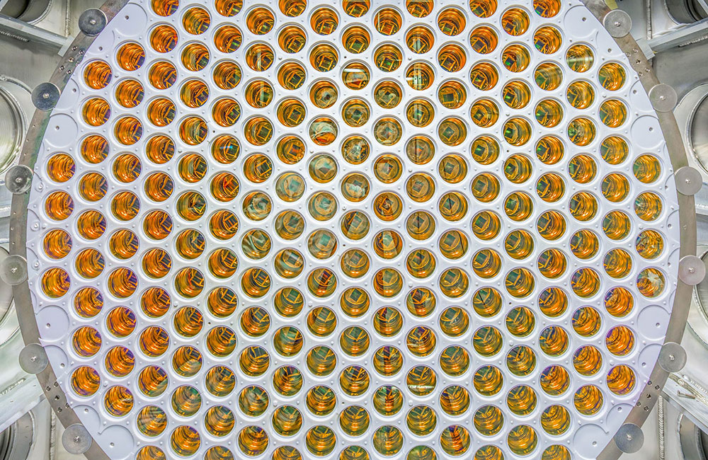 A circular array of amber, glossy photomultiplier tubes arranged in a grid pattern.