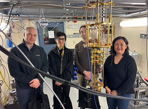 Four people posing in by HAYSTAC experiment at Wright Lab.