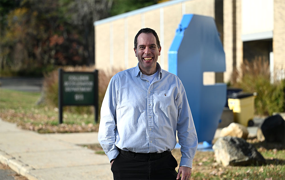 Seth Nemesure stands outside the Collider-Accelerator Division building at Brookhaven Lab