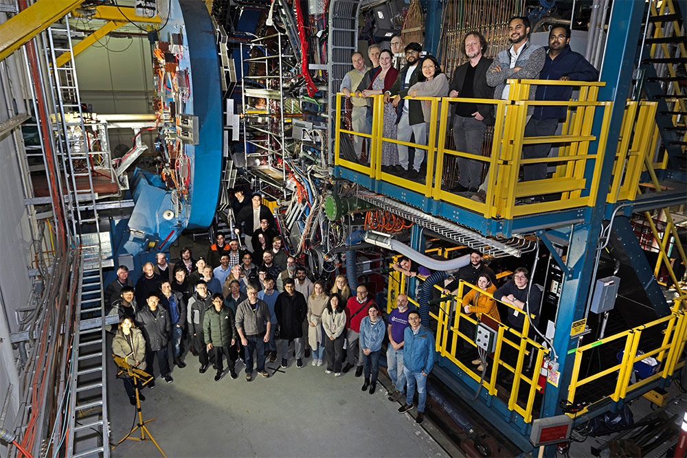 About 50 STAR collaboration members stand on and around platforms beside the STAR detector at the Re