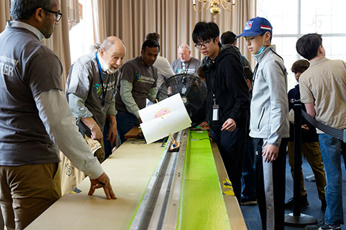 Volunteer judges watch with anticipation as a student releases vehicle onto track