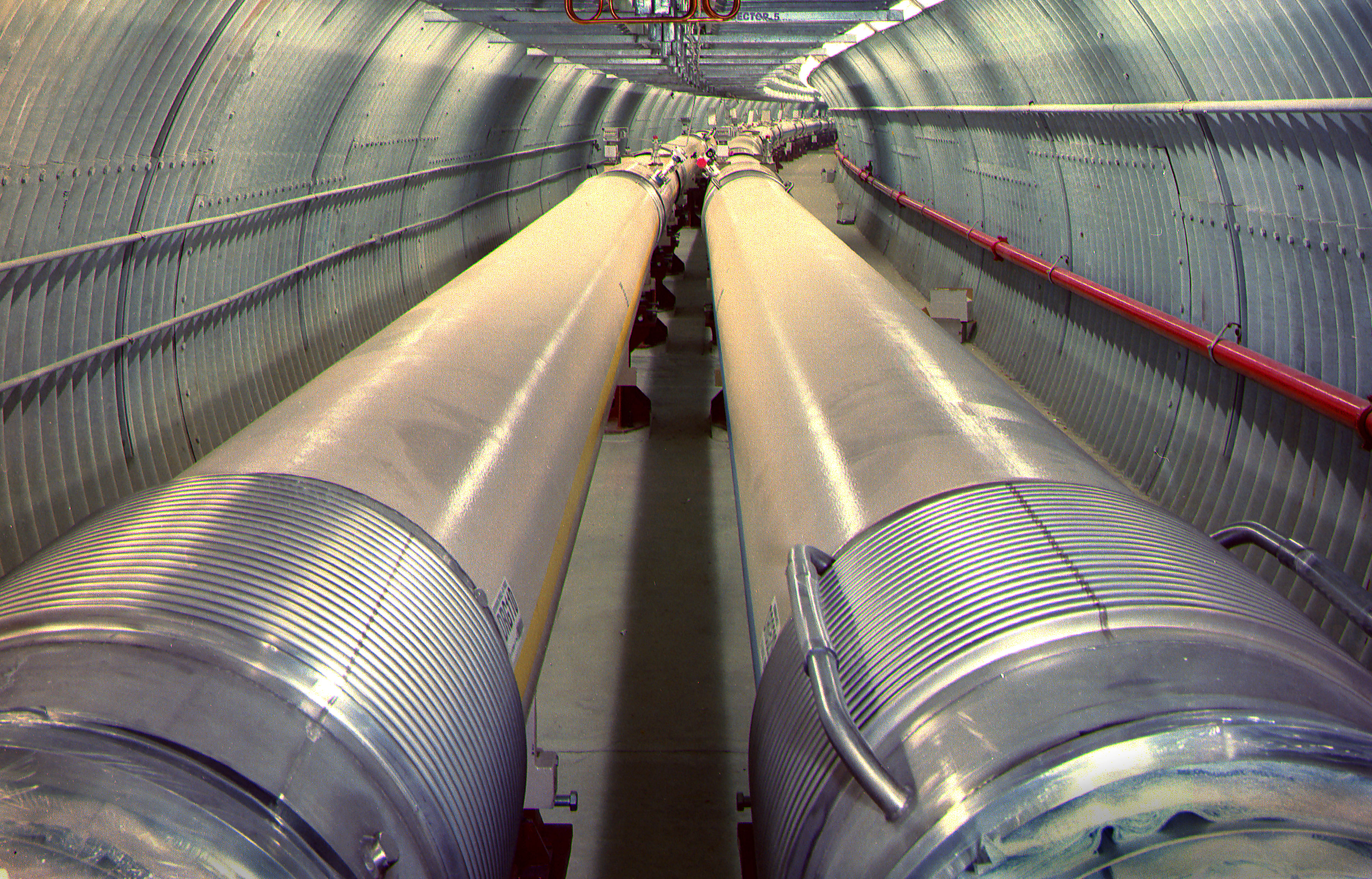 Tunnel of the Relativistic Heavy Ion Collider with parallel beam pipes extending into the distance.