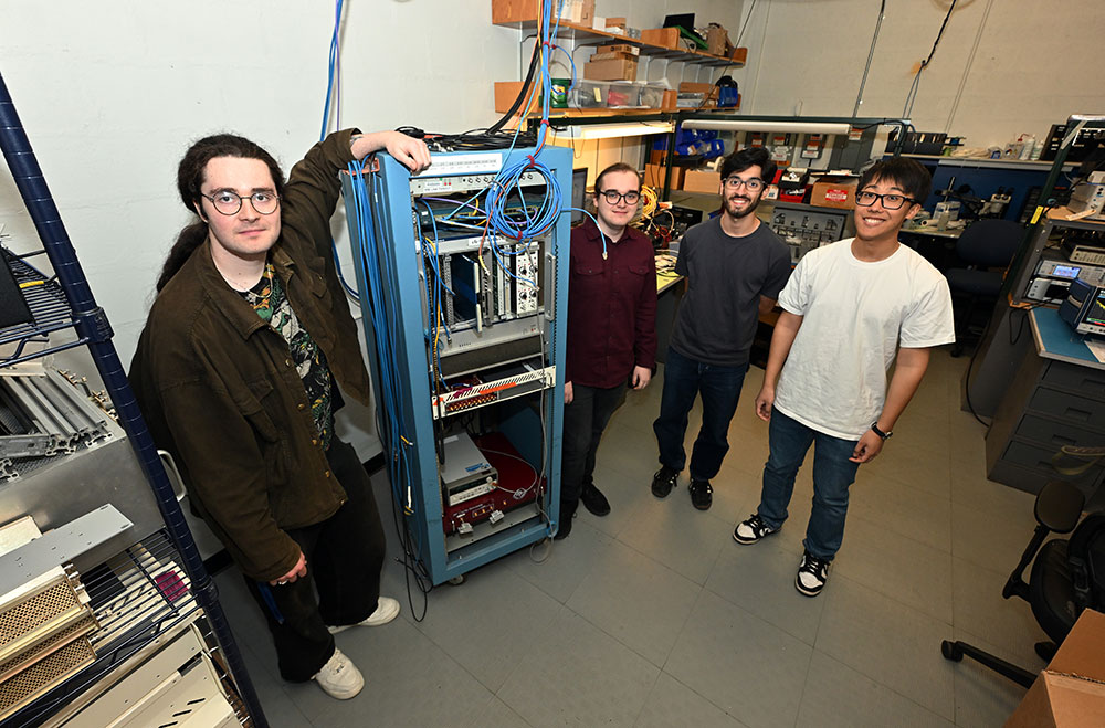 Alex Fahey, Arshdeep Singh, Michael McCooey, and Samson Mai stand in a lab with radiofrequency equip