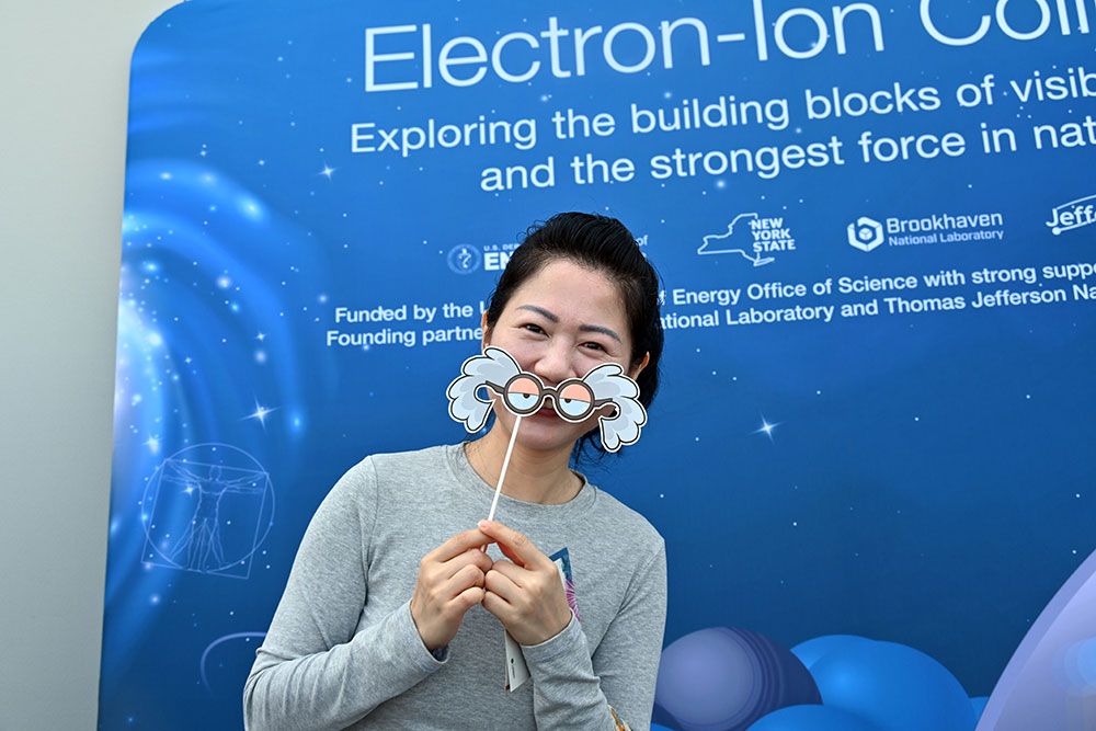 Open house tor visitor holds up an Einstein cartoon mask