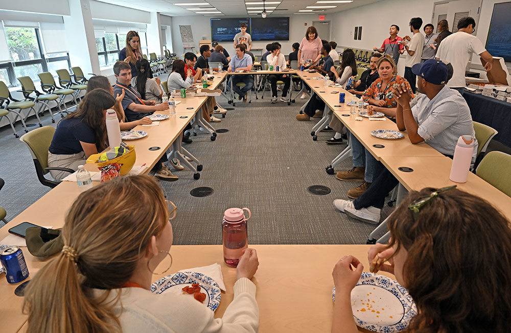 Students and mentors sit around a table during a pizza lunch