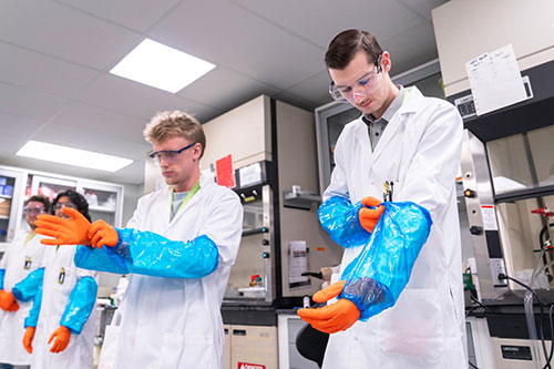 Students putting on PPE gloves and sleeves