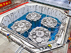 Overhead view of pool filled with four cylinders surrounded by blue liquid
