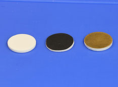 Photo of a white disk, black disk, brown disc placed in a row on a bright blue background