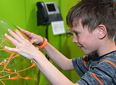 Child hold hands up to on sphere filled with orange streaks of light