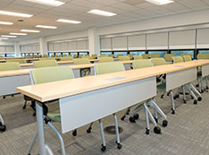 Conference room filled rows of long desks with green chairs