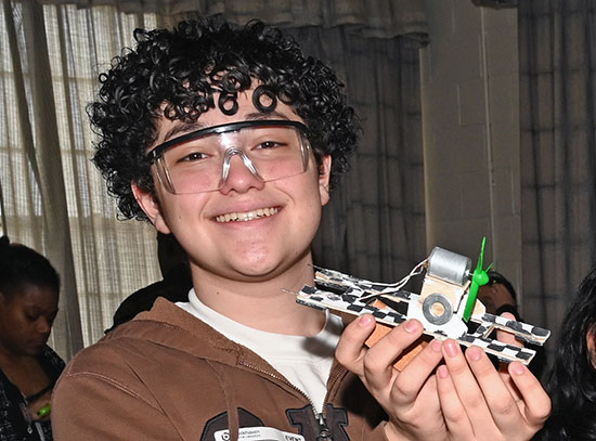 A student holds up small maglev vehicles
