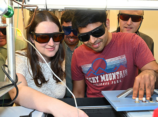 A group of researchers wearing protective glasses while they'll work with lab equipment