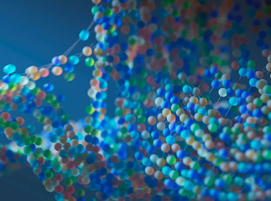 An abstract, macro shot of a blue, red, green, and orange beaded molecular structure, suggesting DNA