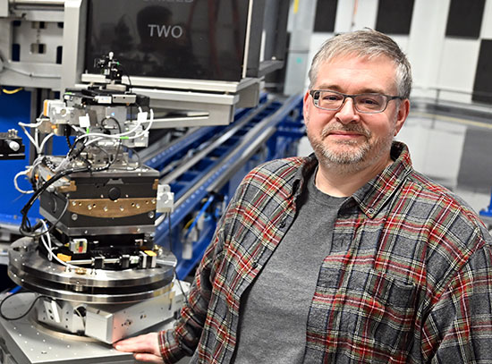Garth Williams stands beside an area detector at the Coherent Diffractive Imaging beamline.
