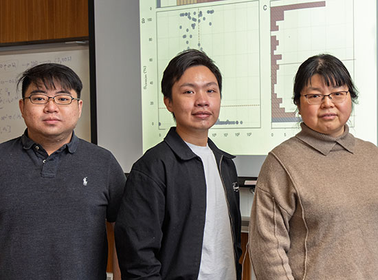 Wenjie Liao, An Nguyen, and Ping Liu stand in front of a projected data slide from a machine learnin
