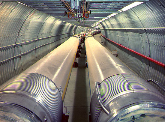 Tunnel of the Relativistic Heavy Ion Collider with parallel beam pipes extending into the distance.